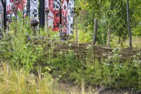 Wicker fence with native planting - What Does Not Burn garden at RHS Hampton Court Palace Garden Festival 2022 - Design: Victora Manoylo, Carrie Preston