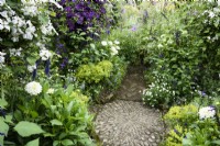 Crossing point of paths marked by a pebble mosaic amongst lush planting in July