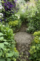 Crossing point of paths marked by a pebble mosaic amongst lush planting in July