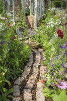 Reclaimed brick and wood chip path by a flower border in Alitex cutting garden at  RHS Hampton Court Palace Garden Festival 2022  