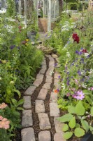 Reclaimed brick and wood chip path by a flower border in Alitex cutting garden at  RHS Hampton Court Palace Garden Festival 2022  