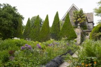 Clipped Yew pyramids and double herbaceous borders in the Canal Garden at York Gate.