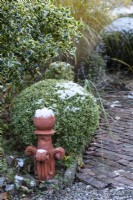 Clay finial in a garden of clipped evergreens in December.