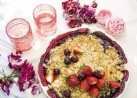 Dish of berry crumble on table decorated with cut rose stems