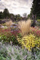 Border edged with Nepeta 'Six Hills Giant' featuring upright Calamagrostis x acutiflora 'Karl Foerster', Persicaria amplexicaulis 'Dark Red' and Veronicastrum virginicum at Whitburgh House Walled Garden in September