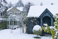 View of garden studio and traditional style greenhouse in town garden in winter with box topiary. December