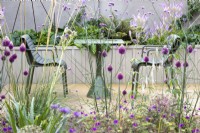 View of a small courtyard garden North Yorkshire sandstone  patio with  metal patio furniture and a wooden raised bed behind. 

Plants include Allium sphaerocephalon, Verbena bonariensis and Veronicastrum virginicum 'Fascination' - culver's root.

Design by Semple Begg Design