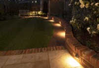 A London garden after a makeover with a new low brick wall and path with downlights.
