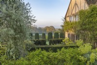 View across hedges of Buxus sempervirens and Taxus baccata towards the distant landscape in a formal country garden in Spring - April