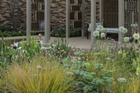 Herbaceous beds planted with lupins, white alliums, geums, astrantias, pimpinella, verbascums and ornamental grasses. in front of pavillion made of willow screens  - Stitchers Sanctuary Garden