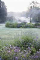  Lavender and geranium borders with distant river mist. Early morning.
