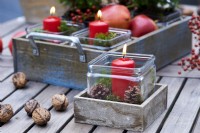 Table arrangement of a red candle in a wooden box and surrounded by wallnuts and candles