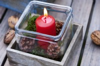 Table arrangement of a red candle in a wooden box and surrounded by wallnuts