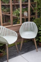 Two garden chairs sitting on paving in front of a cedar greenhouse.

The Gabriel Ash showstand at RHS Chelsea Flower Show 2023.