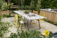 A community table that incorporates two chess boards and is place for people to come together to eat or play games. Plants in the foreground,Trachelospermum jasminoides and Mentha Ã— piperita. The London Square Community Garden, Gold winner - Designer: James Smith