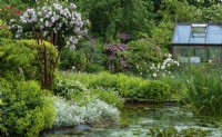 Garden pond surrounded by perennial borders with feature metal sculpture of bullrushes inset - 'The Brambles' Open Garden, Clopton, Suffolk