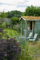 Summerhouse with living roof of sedums, set in perennial border at edge of sloping lawn - Open Gardens Day, Tuddenham, Suffolk