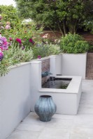 Brick and white rendered raised pool with verdigris fountain basin  incorporated in rendered terrace retaining wall.