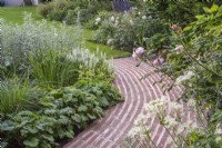 Terracotta brick curved running bond path; border plants include Rosa 'Queen of Sweden' and Salvia sylvestris 'Schneehugel'; Astrantia major 'Large White'