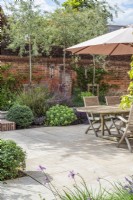 Walled courtyard garden with garden furniture, sandstone paving, dry borders and pleached Pyrus salicifolia 'Pendula' 