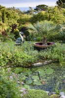 Garden pond overlooked by a decorative metal heron in July