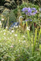 Decorative metal decoy heron amongst lush planting in July