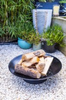 Firepit in gravel garden with small water feature behind