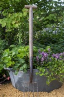 Border fork leaning against recycled metal container with planting - RHS Malvern Spring Festival 2023 - Bee Positive, Bee Kind, Bee Aware - Designers Rick Ford, Katie Gentle
