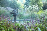 Sculpture in the centre of the Dragon Pond surrounded by Persicaria and ornamental grasses 