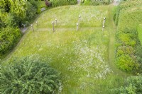 View over meadow with formal avenue of cut grass lined with wooden posts topped with stainless steel globes. June. Summer. Image taken with drone. 