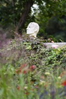 Sculpture of a man's head mounted on a wall in a country garden