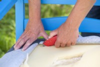 Woman using stanley knife to cut out the foam from the cushion