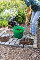 Woman mixing in compost with the soil in the open squares