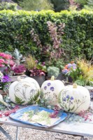 White pumpkins with pressed flowers and leaves on table with berries and eucalyptus sprigs