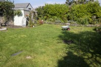 Laying out new borders in a garden, using string to create the edges to be cut