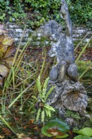 Figure of boy on a dolphin in a pond at Compton Acres, Dorset in November