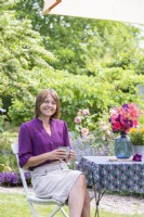 Woman sitting at table with hot drink under parasol