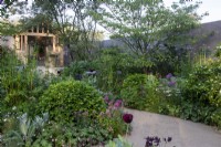 A path winds past herbaceous borders towards an oak pavilion on the RBC Brewin Dolphin Garden designed by Paul Hervey-Brookes - RHS Chelsea Flower Show 2023