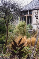 Decorative metal leaf amongst shrubs and grasses in the garden of Balmoral Cottage in December