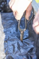 Woman using scissors to poke holes in the compost bag for drainage