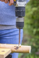 Woman drilling two holes through the top of the birch stick