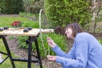 Woman pushing smaller Willow stick through the holes in the larger stick, creating a ring