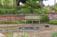 A bench and cat overlook a contemporary slate water feature and rill.