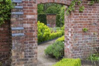 A doorway in the kitchen garden wall frames the view of the formal parterre beyond.