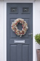 A Countryside Wreath. A florists' wire frame is wrapped in old man's beard, and decorated with rose hips, hawthorn berries, teasels and cedar seed cones.