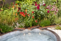 Copper metal rills with water flowing into a small pool - late summer mixed perennial planting of Echinacea purpurea 'Magnus', Echinacea 'Eccentric', Dahlia 'Black Narcissus', Kniphofia 'Papaya Popsicle'