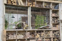 An insect bug hotel made from reclaimed reused salvaged materials and wood off cuts and pine cones for insects habitat