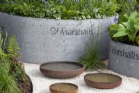 Corten steel bowls filled with water for wildlife to drink - concrete containers with mixed perennial planting of Hosta 'T-Rex' and Brunnera macrophylla 'Jack Frost'