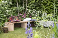 Wooden bench on grass lawn - mixed perennial planting border of Viburnum plicatum and opulus, Digitalis purpurea 'Albiflora', Roses, Betula pendula and Fagus sylvatica hedge 