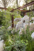 Rusty steel frame pergola with concrete suspended sculptures - mixed perennial planting including Aralia chapaensis, Silene fimbriata, Euphorbia lathyris and Imperata 'Red Baron' - Japanese blood grass 